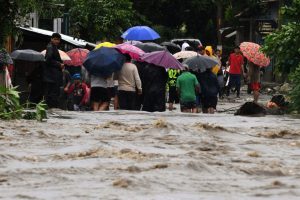 People walk away from the flooded Bermejo river in San Pedro Sula, Honduras, due to the heavy rains left by tropical storm Sara on November 16, 2024. Tropical storm Sara left 45,329 people affected in Honduras, of which more than a thousand have been left homeless or taken to shelters, according to local authorities. (Photo by Orlando SIERRA / AFP) (Photo by ORLANDO SIERRA/AFP via Getty Images)