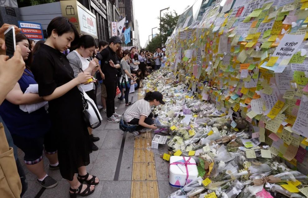 A woman places a flower in memory of a South Korean woman who was stabbed to death at the exit of the Gangham subway station in Seoul on May 21, 2016.