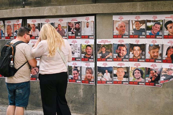 File - Two people in the Czech Republic in front of the posters of those kidnapped by Hamas on October 7, 2023