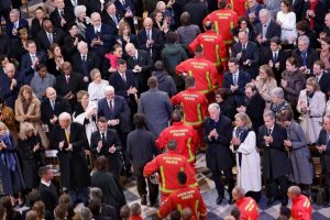 Firefighters, rescuers and builders involved in the restoration walk around the ship in front of attendees, including world leaders and dignitaries.