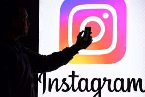 File - FILED - 15 March 2019, Schleswig-Holstein, Aukrug-Homfeld: A person holds a smartphone in front of a monitor with the logo of social media platform Instagram. Photo: Carsten Rehder/dpa/Archivbild