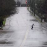 A pedestrian walks down a rain-soaked street in Dallas, Thursday, Dec. 26, 2024. (AP Photo/LM Otero)