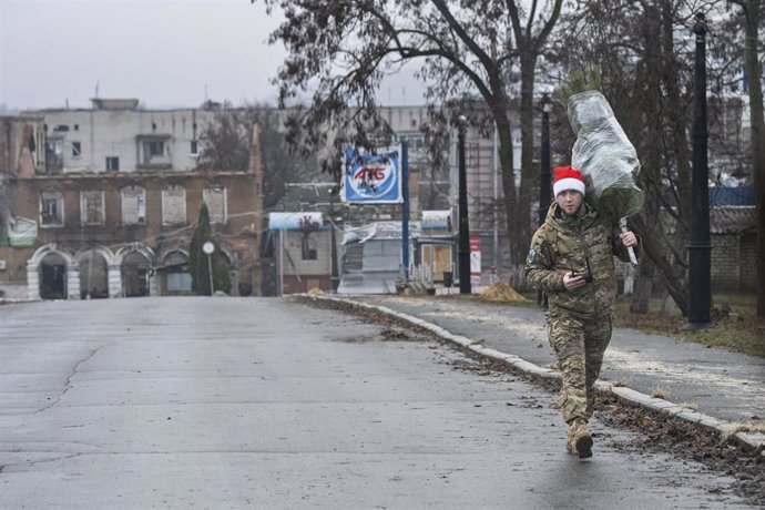 A Ukrainian soldier carries a Christmas tree in Kharkiv