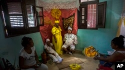 FILE - Marisa Ramírez Gutiérrez, standing in the center, remains motionless on her symbolic throne dressed in the tunic of the "Iyawo"or girlfriend, in Havana, Cuba, on September 11, 2015.