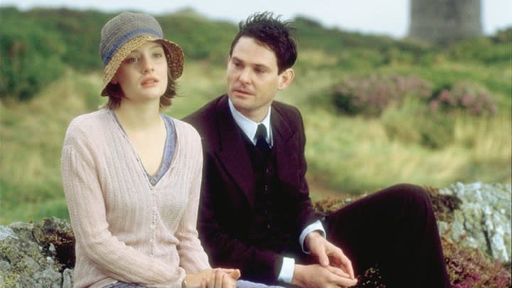 Ramola Garai and Henry Thomas as Cassandra and Simon sitting on an outdoor bench in I Capture the Castle.