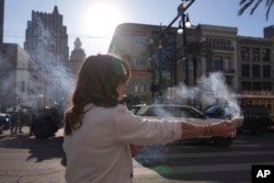 Stephanie Drake burns sage at Canal and Bourbon Street on January 2, 2025 in New Orleans.