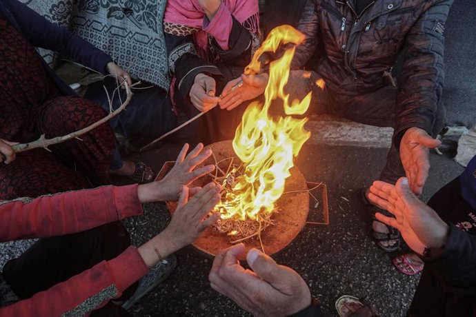 Displaced Palestinians warm themselves with fire in the Gaza Strip