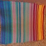 Image of a handwoven blanket with a variety of colors.