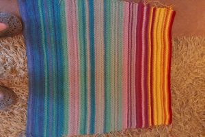 Image of a handwoven blanket with a variety of colors.